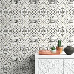 a white cabinet sitting in front of a wall with a plant on top of it