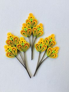 three yellow and green flowers are on a white surface, one is in the shape of a flower