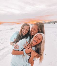 three girls hugging each other on the beach