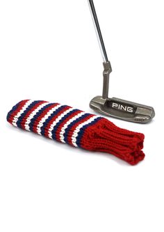 a red, white and blue knitted golf club headcover next to a putter