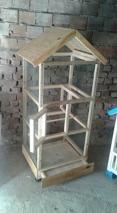 a small bird cage sitting on top of a wooden stand next to a brick wall