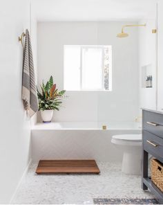 a bathroom with a toilet, sink and bathtub next to a window on the wall