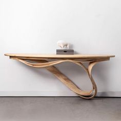 a wooden shelf sitting on top of a floor next to a white wall with an object on it