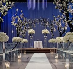 the aisle is lined with clear vases filled with white flowers and candles for an elegant wedding