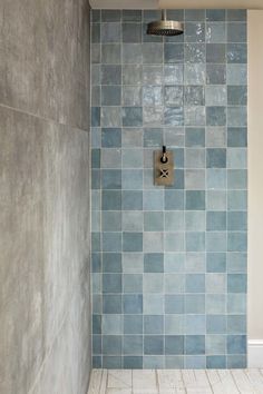 a bathroom with blue tiled walls and flooring, including a shower head in the corner