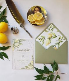 the wedding stationery is laid out with lemons and greenery