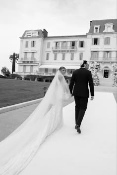 the bride and groom are walking down the walkway in front of an elegant building with large balconies