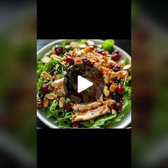 a salad with chicken, cranberries and nuts in it on a white plate