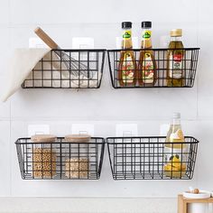 two metal baskets holding food and condiments on the wall above a counter top