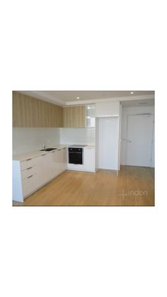 an empty kitchen with wooden floors and white cabinets