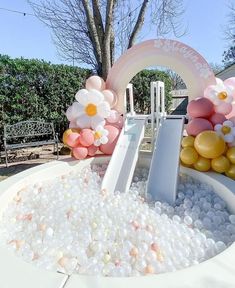 an inflatable ball pit with flowers and balloons on the top is surrounded by white rocks