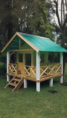 a small wooden cabin in the middle of a grassy area with stairs leading up to it