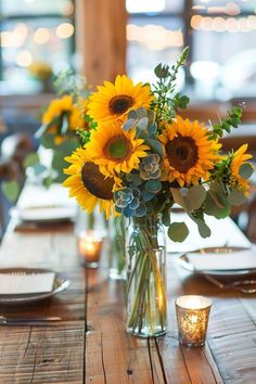 a vase filled with sunflowers sitting on top of a wooden table next to candles