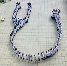 a large group of people standing in the shape of a circle on top of a tiled floor