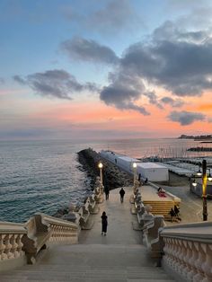 people are walking up and down the stairs near the water at sunset or sunrise time