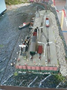 an aerial view of a model train track with people standing on the tracks next to it