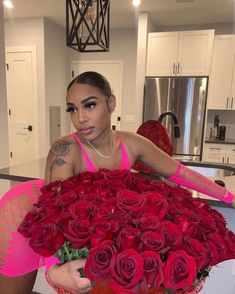 a woman holding a large bouquet of roses in her hands and posing for the camera