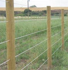 a wire fence in the middle of a grassy field