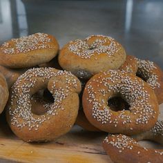 several bagels with sesame seeds sit on a cutting board