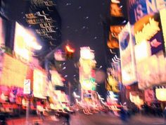 a blurry photo of a city street at night with lots of lights and signs