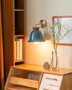 a wooden desk with a lamp and some books on it, next to a bookcase