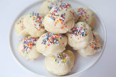 a white plate topped with donuts covered in frosting and sprinkles