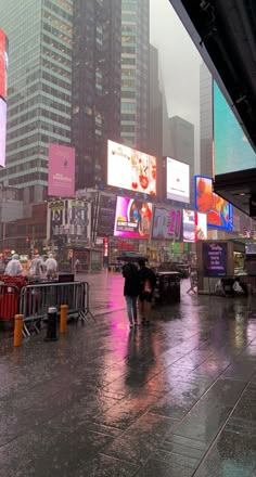 people walking in the rain with umbrellas and shopping carts on a city street near tall buildings