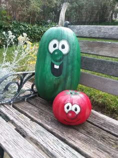 two painted pumpkins sitting on top of a wooden bench