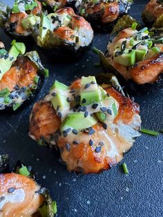 sushi rolls with salmon, avocado and sesame seeds on a black surface