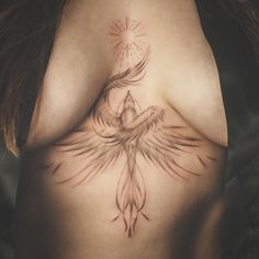 a woman's chest with a bird tattoo on her left side ribcage