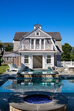 a house with a pool in front of it and a fire pit on the side