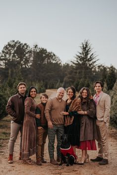 a group of people standing next to each other on a dirt road with trees in the background