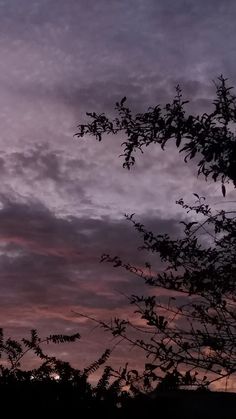 the sun is setting behind some trees and clouds