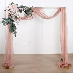 a pink wedding arch decorated with flowers and greenery