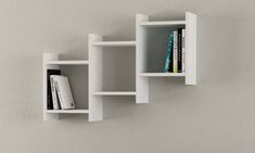 two white shelves with books on them against a wall