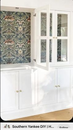 an empty room with white cabinets and floral wallpaper