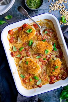 a casserole dish with meatballs, tomatoes and spinach garnish