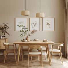 a dining room table with chairs and pictures on the wall above it, along with two vases filled with flowers