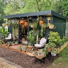 a small garden shed with lots of potted plants on the porch and patio area