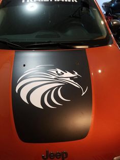 an orange car with a black eagle decal on it