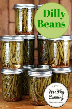 six jars filled with green beans sitting on top of a wooden table next to a sign that says dilly beans