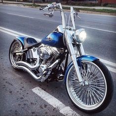 a blue motorcycle is parked on the side of the road with chrome rims and spokes