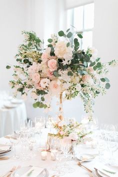 an elegant centerpiece with flowers and greenery is displayed on a table at a wedding reception