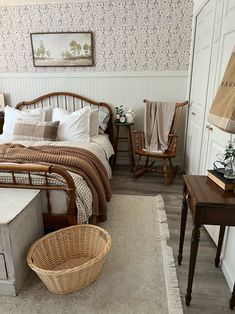 a bed sitting in a bedroom next to two wooden chairs and a table with a basket on it