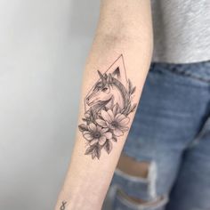 a woman's arm with a unicorn and flowers tattoo on the left side of her arm