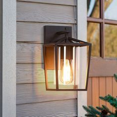 a light that is on the side of a house next to a tree and window