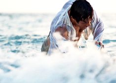 a man in white shirt on surfboard in water