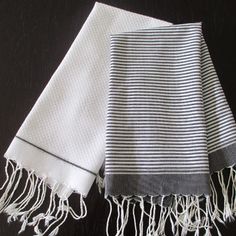 two black and white striped towels on a dark tablecloth with one folded in half