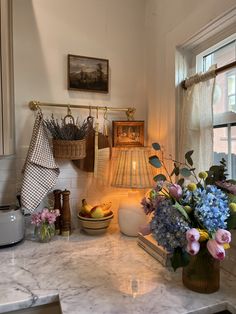 the kitchen counter is covered with flowers and other items in vases next to an open window