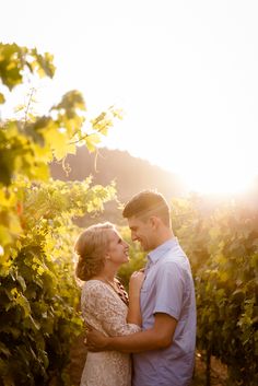 a man and woman standing next to each other in a vineyard